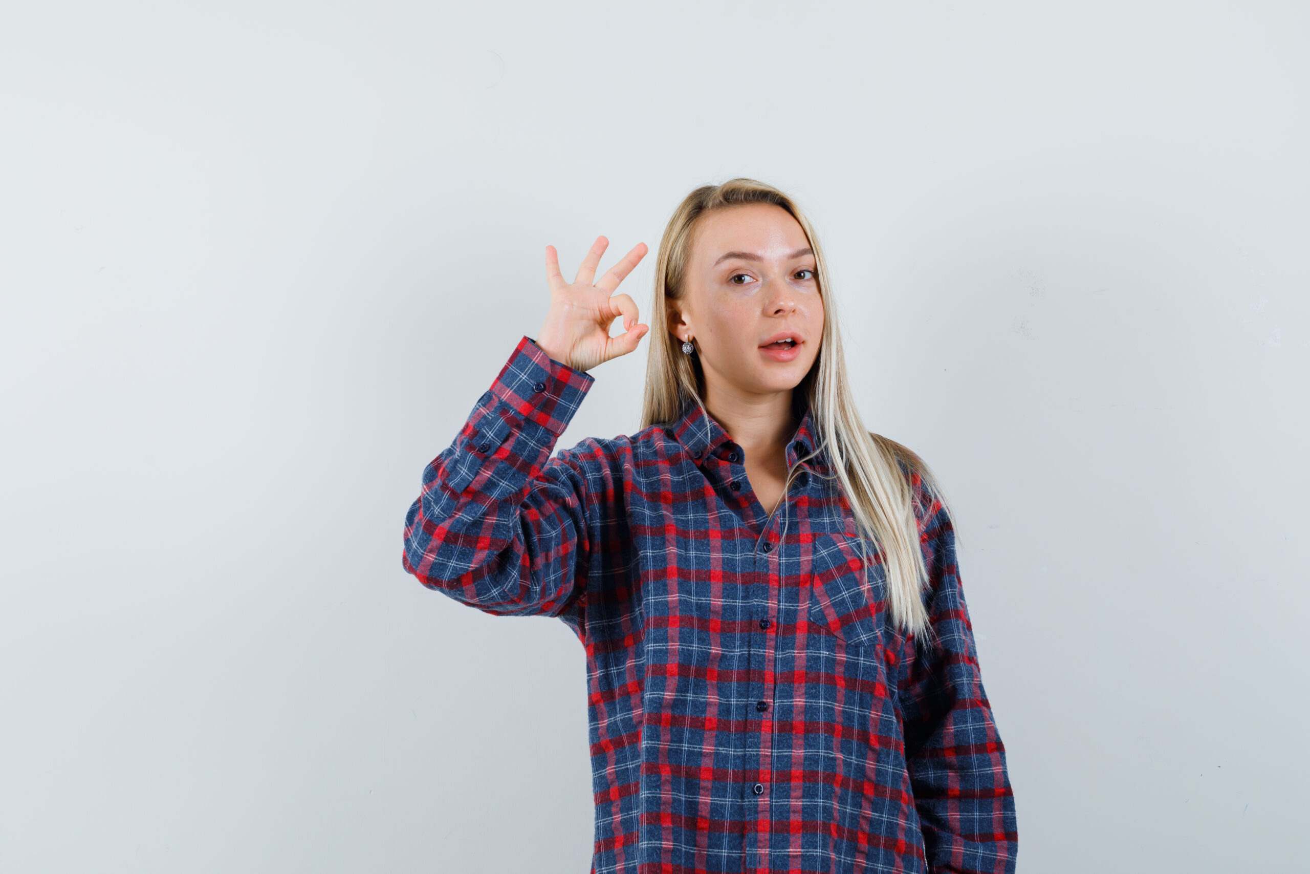 blonde lady showing ok gesture in casual shirt and looking jolly. front view.
