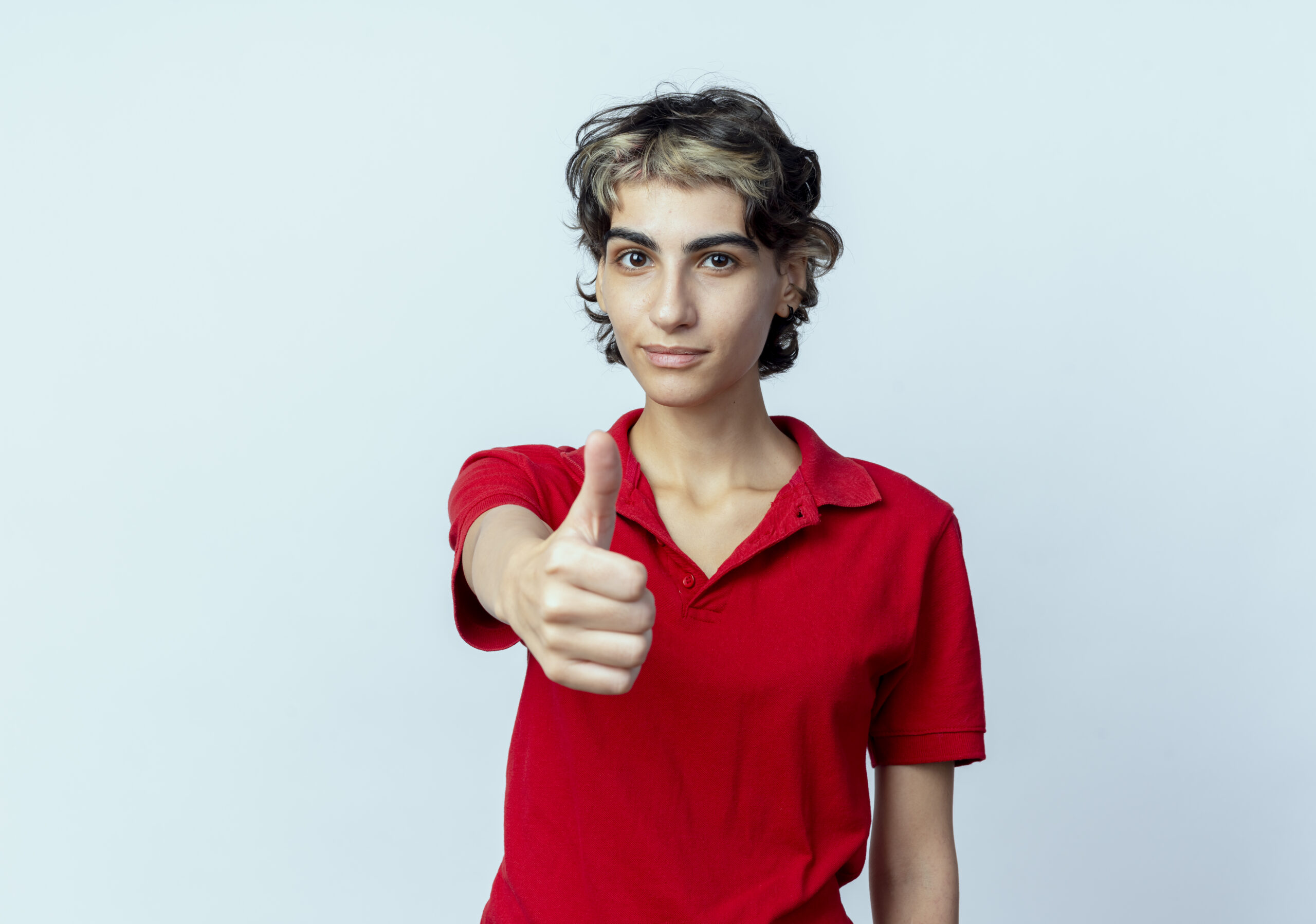 confident young caucasian girl with pixie haircut stretching out hand at camera showing thumb up isolated on white background with copy space